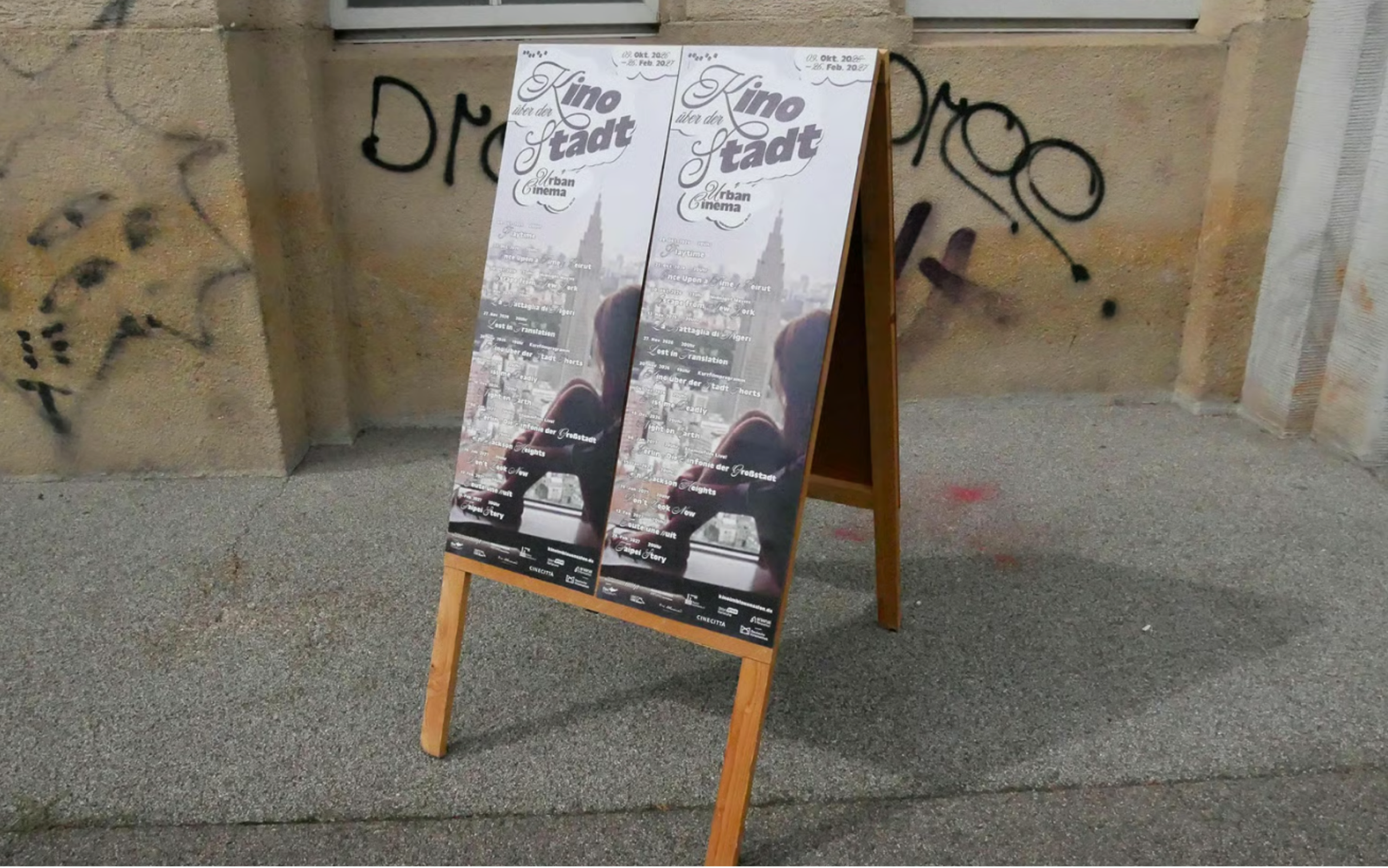 Poster der Reihe "Kino im Blauen Salon", "Kino in der Stadt" auf einem aufklappbarem Plakataufsteller aus Holz